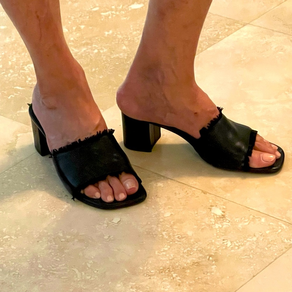 Black leather low-heeled slides with fringe accents